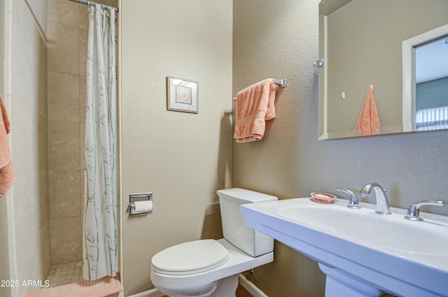 bathroom featuring sink, a shower with shower curtain, and toilet