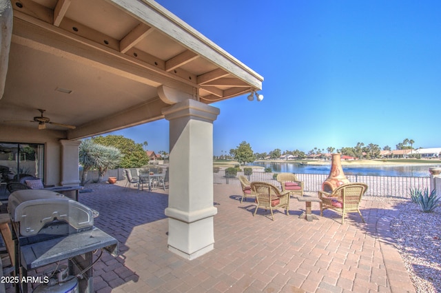 view of patio with a water view, a grill, outdoor lounge area, and ceiling fan