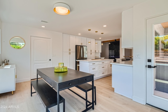 kitchen with white cabinets, light hardwood / wood-style floors, stainless steel refrigerator, and pendant lighting