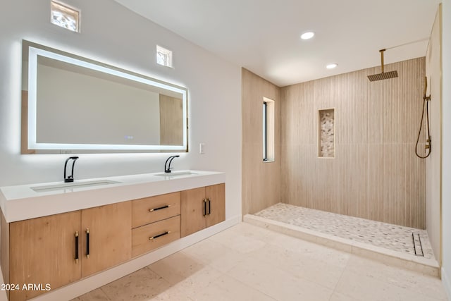 bathroom with tile flooring, tiled shower, and dual bowl vanity