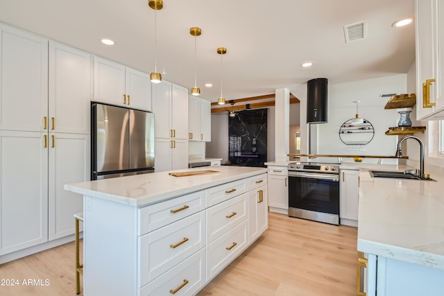 kitchen with light stone countertops, hanging light fixtures, stainless steel appliances, light hardwood / wood-style floors, and sink