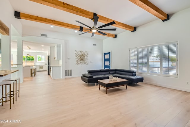 living room with beamed ceiling, light hardwood / wood-style flooring, and ceiling fan