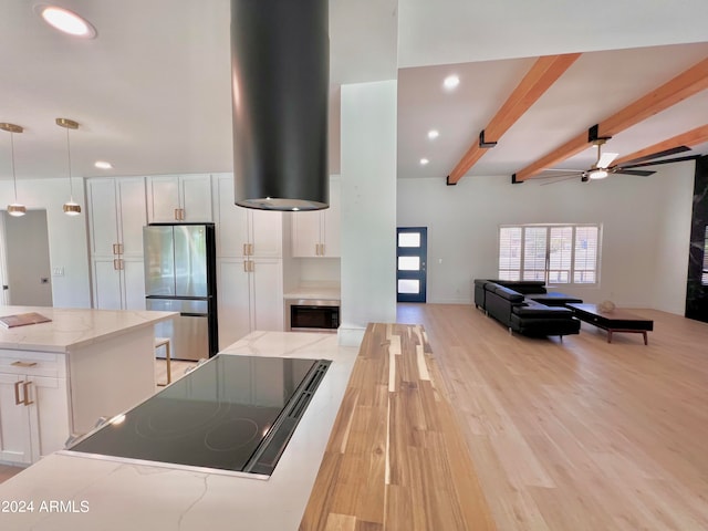 kitchen with beamed ceiling, light wood-type flooring, appliances with stainless steel finishes, and white cabinetry