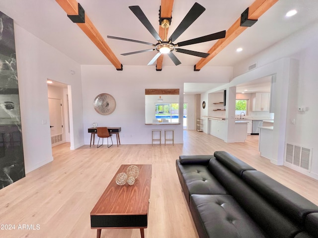 living room featuring light hardwood / wood-style floors, ceiling fan, and beamed ceiling