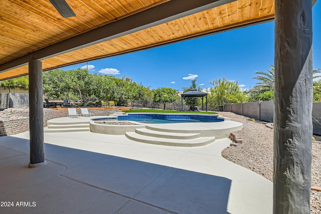 view of patio with a swimming pool with hot tub and a gazebo