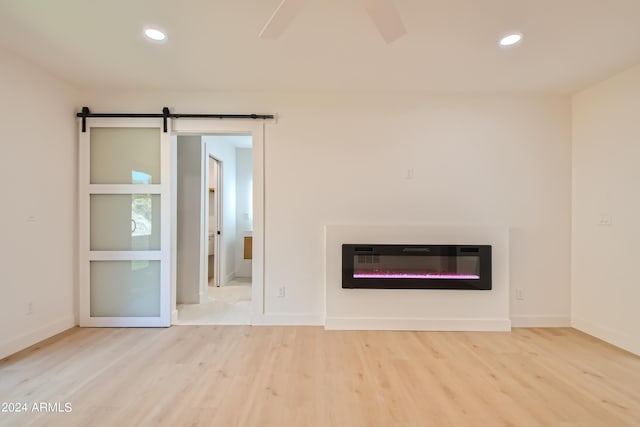 unfurnished living room featuring light hardwood / wood-style flooring and a barn door