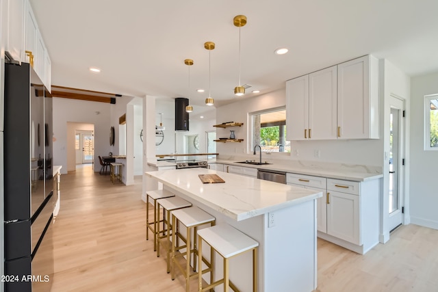 kitchen with hanging light fixtures, light wood-type flooring, white cabinetry, a kitchen island, and dishwasher