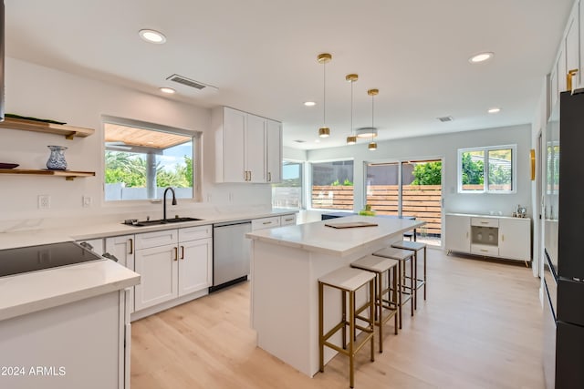 kitchen featuring white cabinets, light hardwood / wood-style flooring, sink, stainless steel dishwasher, and a kitchen island