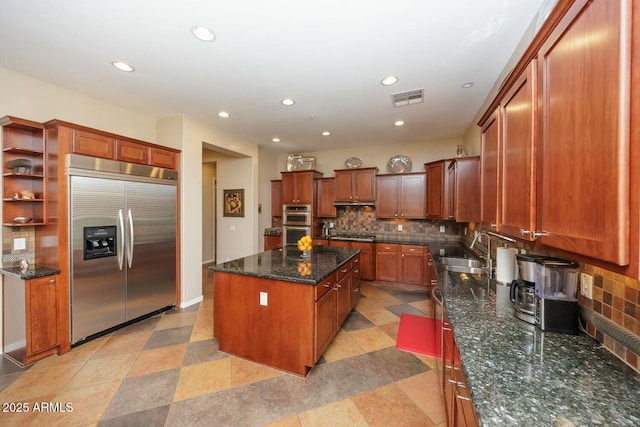 kitchen featuring appliances with stainless steel finishes, sink, dark stone countertops, backsplash, and a center island