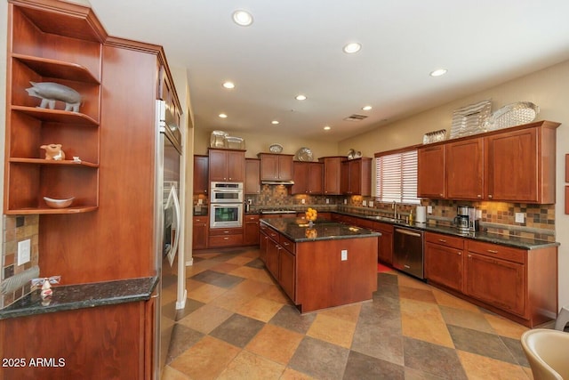 kitchen with sink, stainless steel appliances, tasteful backsplash, a kitchen island, and dark stone counters