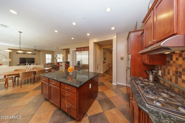 kitchen with dark stone countertops, backsplash, hanging light fixtures, a center island, and stainless steel appliances