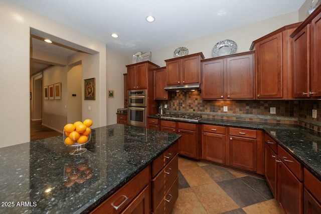 kitchen with appliances with stainless steel finishes, decorative backsplash, and dark stone countertops