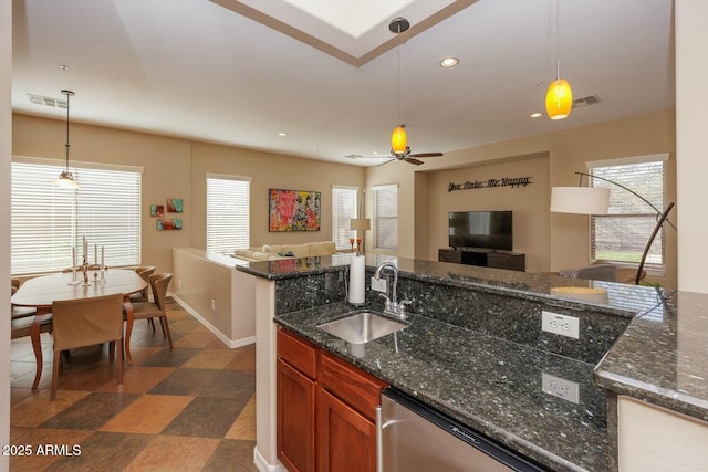 kitchen with sink, hanging light fixtures, dark stone countertops, stainless steel dishwasher, and ceiling fan