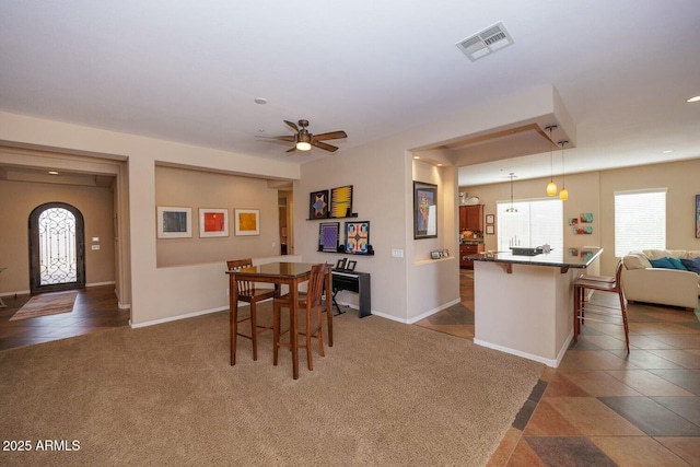 dining space with ceiling fan and dark carpet