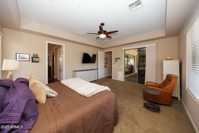 carpeted bedroom featuring a tray ceiling and ceiling fan