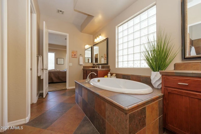 bathroom featuring vanity and tiled tub