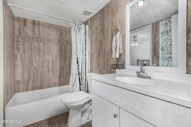 full bathroom featuring ceiling fan, vanity, wood walls, toilet, and shower / tub combo with curtain