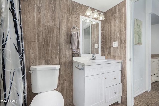 bathroom featuring tile walls, vanity, and toilet