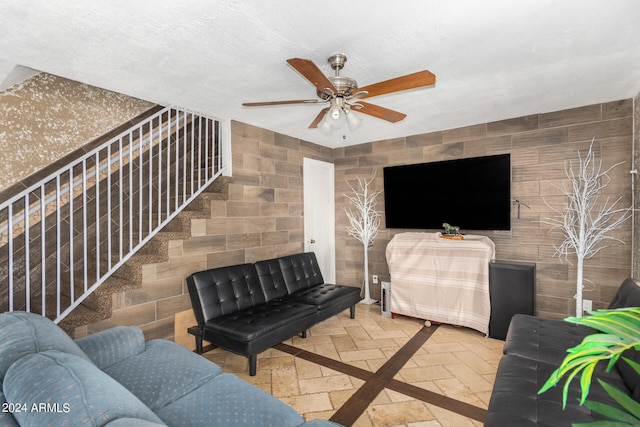 living room featuring ceiling fan and tile walls