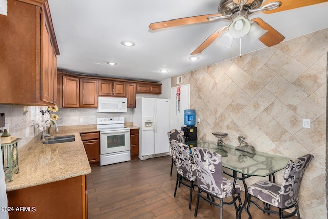 kitchen with light stone counters, dark hardwood / wood-style floors, sink, white appliances, and ceiling fan