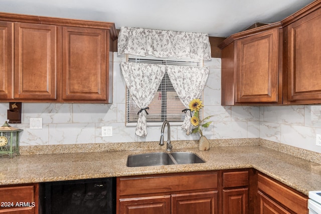 kitchen featuring decorative backsplash, light stone countertops, and sink