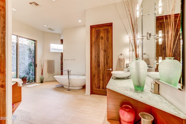 bathroom featuring a bathtub, tile flooring, and vanity with extensive cabinet space