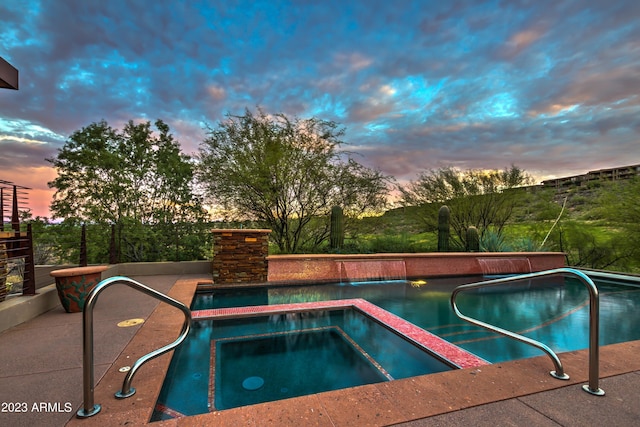 pool at dusk with an in ground hot tub