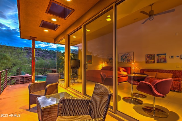 patio terrace at dusk with ceiling fan, an outdoor hangout area, and a balcony