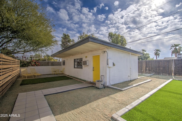 view of outbuilding with a wall mounted air conditioner and a yard