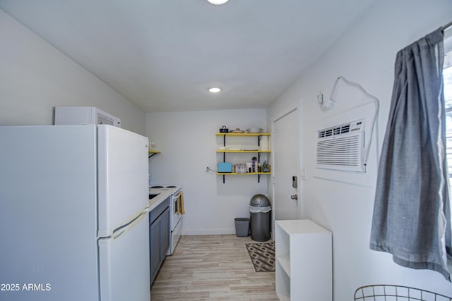 kitchen featuring white appliances, light hardwood / wood-style floors, and an AC wall unit