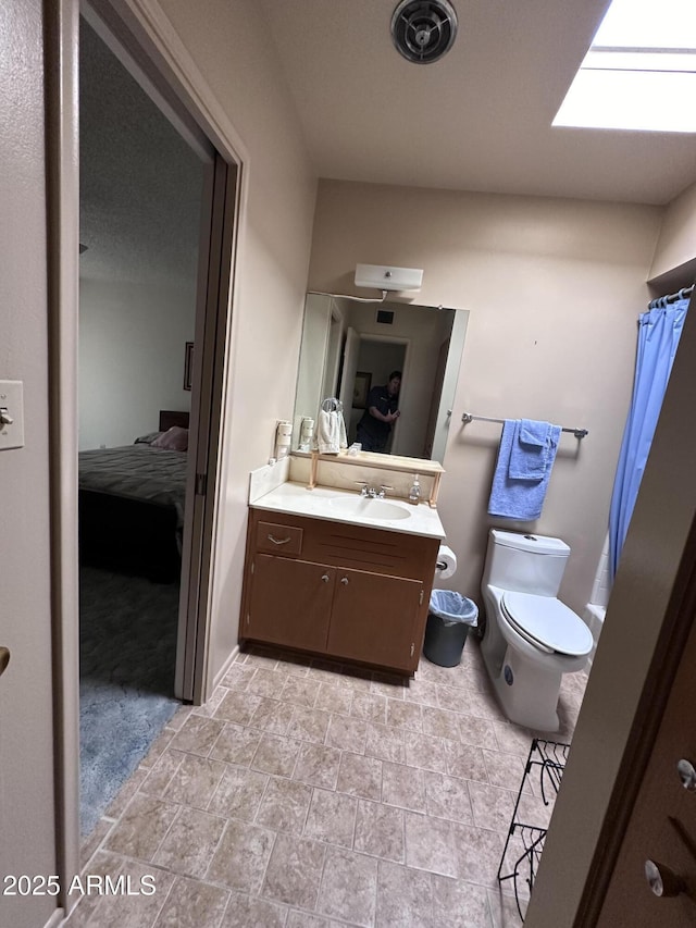 ensuite bathroom featuring toilet, vanity, stone finish floors, and a shower with curtain