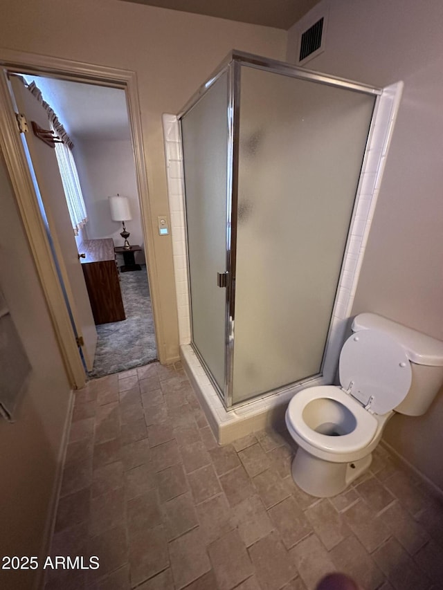 full bathroom with a stall shower, baseboards, and toilet