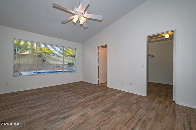 unfurnished bedroom with vaulted ceiling, a spacious closet, a closet, and dark hardwood / wood-style floors