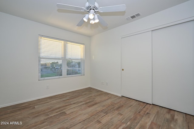 unfurnished bedroom featuring ceiling fan, wood-type flooring, and a closet