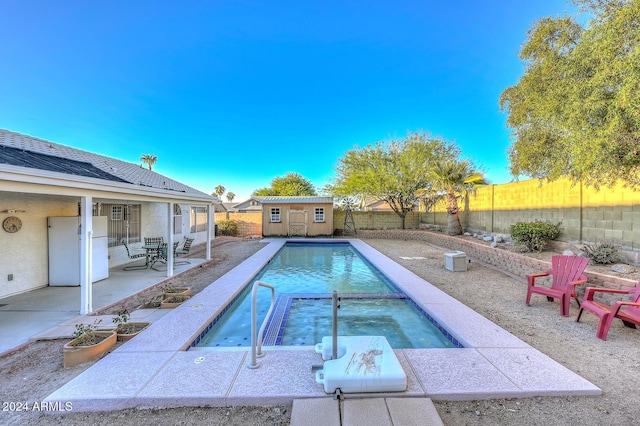 view of pool with an in ground hot tub, a patio, and an outdoor structure