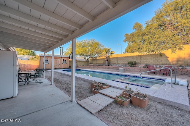 view of pool featuring an in ground hot tub and a shed