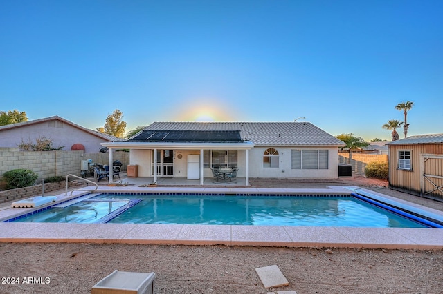 view of pool featuring a jacuzzi, a shed, and a patio area