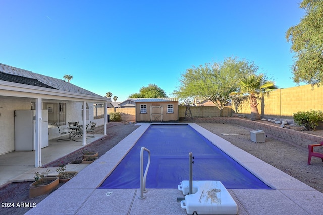 view of pool featuring a patio and a storage shed