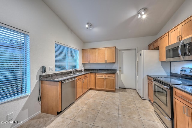 kitchen with a wealth of natural light, light tile patterned floors, stainless steel appliances, and vaulted ceiling