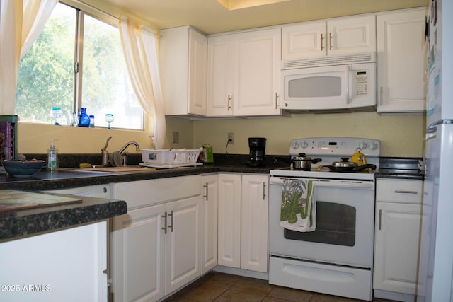 kitchen with white cabinetry, sink, white appliances, and dark tile patterned floors