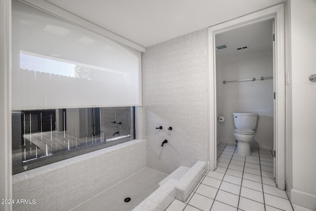 bathroom featuring a tile shower, tile patterned flooring, and toilet