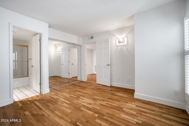 unfurnished bedroom with ensuite bath and light hardwood / wood-style floors