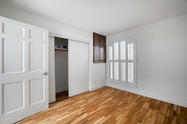 unfurnished bedroom with light hardwood / wood-style flooring and a closet