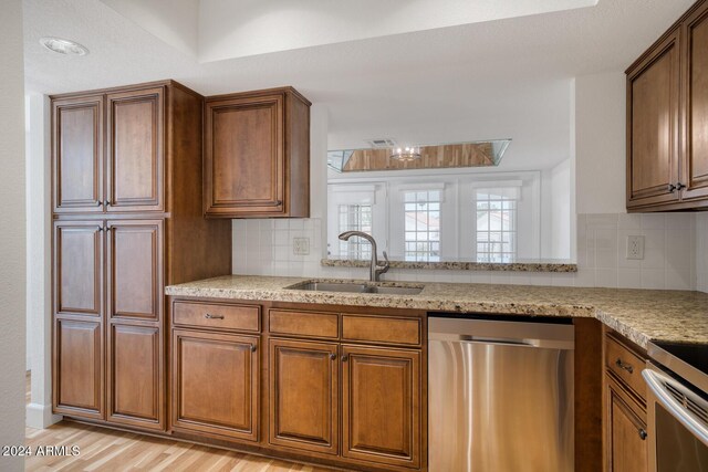 kitchen featuring light stone counters, sink, tasteful backsplash, dishwasher, and light wood-type flooring