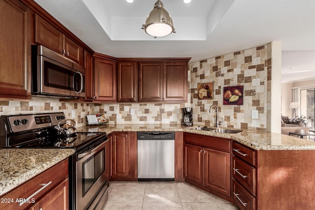 kitchen featuring light stone countertops, stainless steel appliances, decorative backsplash, sink, and a raised ceiling