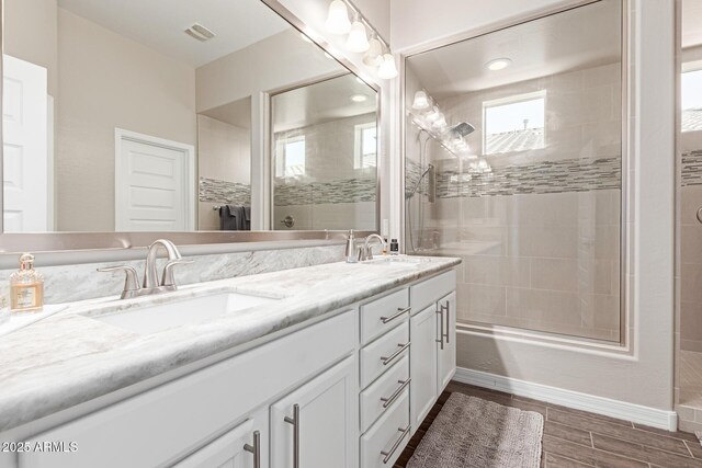 12035 S 186th Ave, Goodyear, AZ 85338 - bathroom with double vanity, tiled shower, wood finish floors, and baseboards