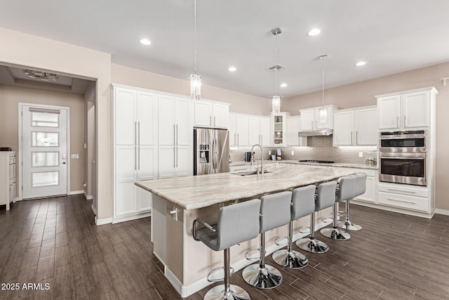 12035 S 186th Ave, Goodyear, AZ 85338 - kitchen with stainless steel appliances, a sink, white cabinets, decorative backsplash, and a kitchen bar