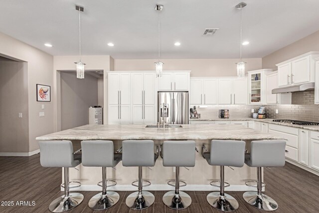12035 S 186th Ave, Goodyear, AZ 85338 - kitchen featuring stainless steel refrigerator with ice dispenser, tasteful backsplash, dark wood finished floors, a kitchen island with sink, and glass insert cabinets