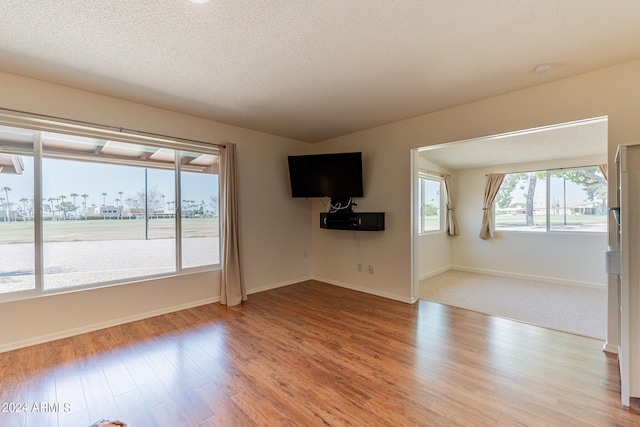 unfurnished living room with light hardwood / wood-style floors and a textured ceiling