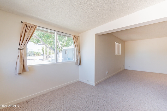 carpeted empty room with a textured ceiling